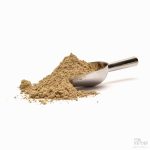 Malt kardemomme med metallskje på hvit bakgrunn