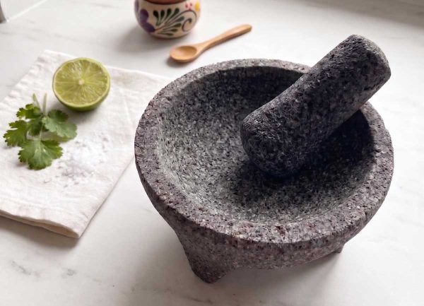 Molcajete i lavastein med tejolote på hvit marmorbenk