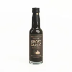 En flaske med Ghost Garlic Hot Sauce og sort innhold grunnet sort hvitløk