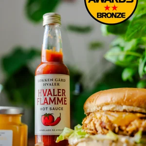 Løkken Hvaler Flamme hot saus stående ved siden av en lekker hamburger